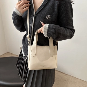 Minimalist cream lychee leather bucket bag with top handles and adjustable strap