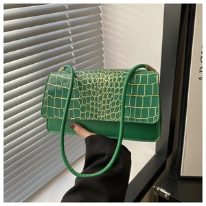 Detail of bright green crocodile pattern shoulder bag with glossy finish and strap