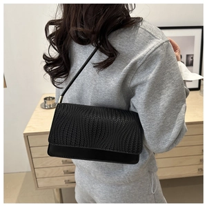 Detail of black leather shoulder bag featuring unique radial textured weave and gold hardware