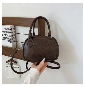 Detail of retro dark brown leather boston bag with embossed text and top handles