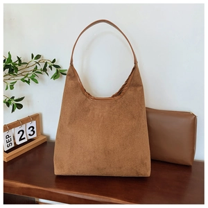 Detail of caramel suede hobo tote bag and matching zippered pouch on wooden surface