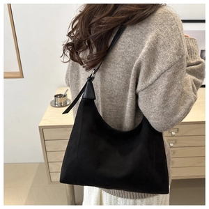 Detail of minimalist black suede hobo bag with sleek shoulder strap shown on a model