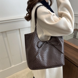 Retro dark brown woven tote bag with leather bow accent shown on shoulder