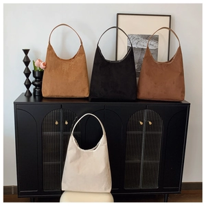 Close-up of minimalist hobo tote bags in four solid colors on a vintage cabinet