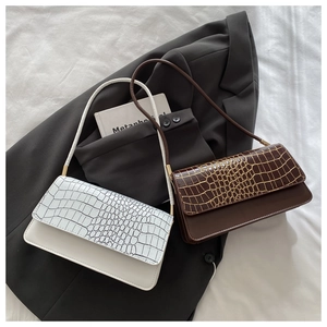 Detail of faux leather underarm bag featuring crocodile embossed texture and gold hardware