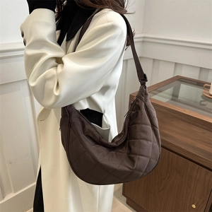 Sac hobo marron en nylon matelassé avec bandoulière ajustable porté par un mannequin