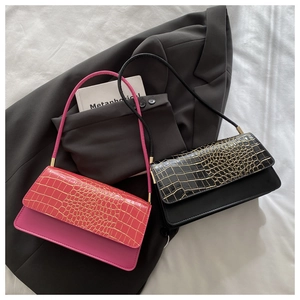 Detail of pink and black faux crocodile leather bags with metal bar trim on a blazer