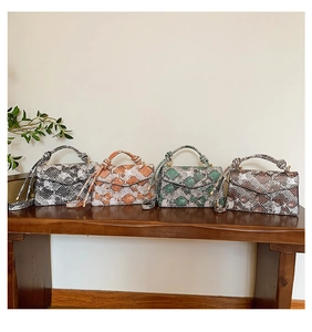 Detail view of stylish snakeskin pattern handbags in four colors on a bench