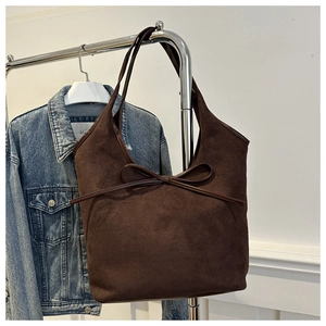 Détail du sac cabas en daim marron foncé avec un nœud minimaliste pour le quotidien