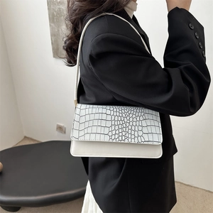 White leather underarm bag with black croc pattern flap and gold hardware on model