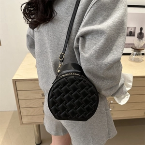 Minimalist black round crossbody bag with quilted weave texture and golden zippers