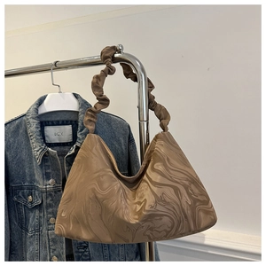 Detail of marble pattern shoulder bag with a stylish brown scrunchie handle design