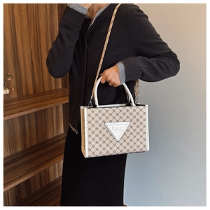 Close-up of beige tote bag featuring floral print and white triangle brand patch