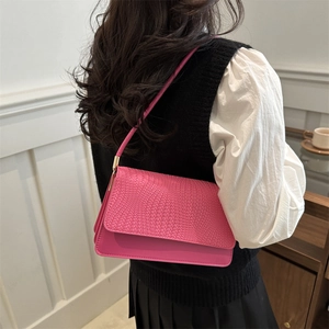 Chic pink shoulder bag with woven texture lid and gold hardware worn by model