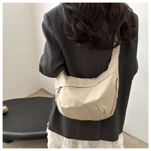 Detail of beige crescent crossbody bag with pleated nylon fabric and wide shoulder strap
