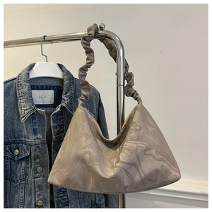 Detail of taupe pleated hobo bag with sand marble texture on a stainless steel hanger