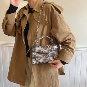 Chic snake-print crossbody bag with top handle and envelope flap worn with trench coat