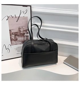 Détail d'un sac cabas bowling en similicuir noir lisse avec longues anses et poche frontale