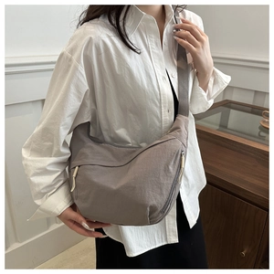 Detail of dark gray nylon crescent bag featuring side zipper with yellow pull cord accent