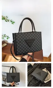 Detail of black tote bag with retro monogram print and triangular leather logo patch