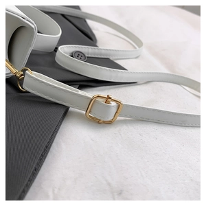 Close-up of white leather shoulder strap with gold-tone adjustable metal buckle and clasp