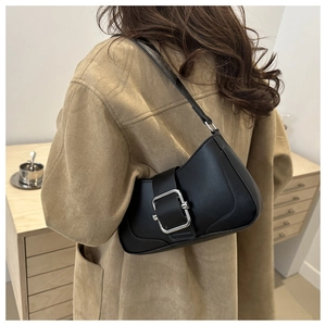 Sac baguette minimaliste en cuir noir avec grande boucle en métal porté à l'épaule
