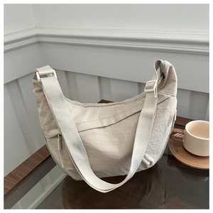 Detail of beige nylon crescent bag with wrinkled texture on a cozy wooden cafe table