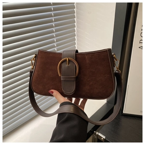 Detail of vintage coffee suede handbag with a prominent aged gold round metal buckle