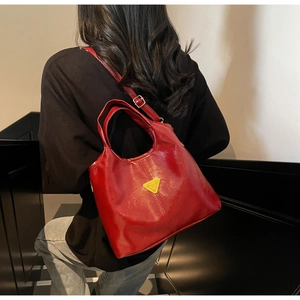 Detailed view of the dark red glossy leather bucket bag with a golden triangle logo plaque