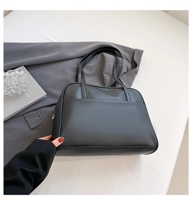 Sac fourre-tout noir minimaliste en cuir avec poche avant fonctionnelle sur fond blanc