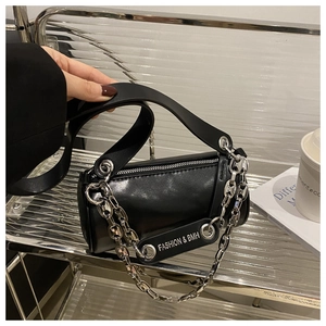 Détail du sac cylindrique noir avec grosse chaîne argentée et large bandoulière en cuir
