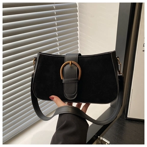 Detail of vintage matte black shoulder bag featuring gold buckle and suede texture