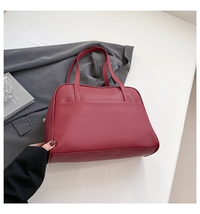 Gros plan d'un sac cabas bordeaux en similicuir avec fermeture éclair latérale en métal
