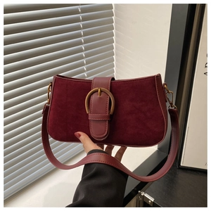 Detail of burgundy vintage baguette bag featuring textured matte finish and gold buckle