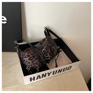 Detail view of leopard print shoulder bag with black leather strap in a gift box