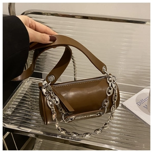 Détail d'un sac oreiller en cuir marron avec chaîne argentée et large bandoulière