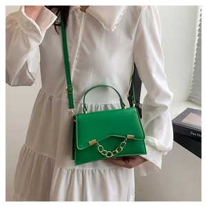 Detail of green leather handbag with gold chain ornament and elegant shoulder strap