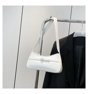 Detail of a white leather baguette bag with a metal buckle strap and shoulder strap