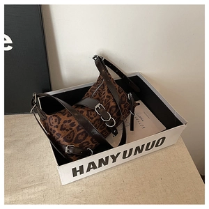 Detailed view of leopard print barrel bag with silver hardware and adjustable leather strap