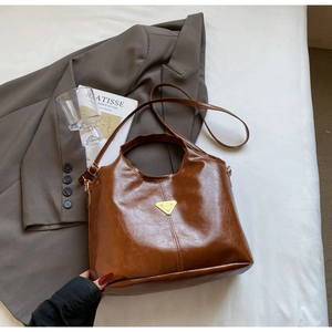 Detailed view of caramel leather tote bag with gold triangle logo and top handle