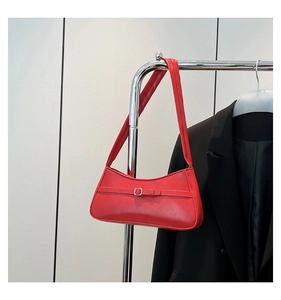 Detail of red leather hobo bag with silver buckle hanging on a metal clothing rack