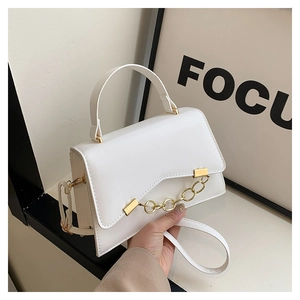 Detailed view of the white leather crossbody bag with a thick gold chain and top handle