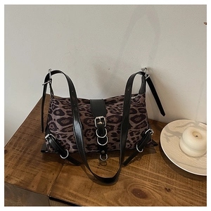 Detail of leopard print tote bag featuring black leather straps and silver metal buckles