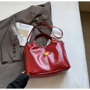 Close-up of wine red glossy leather tote bag featuring gold triangular hardware detail