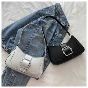 Flat lay of black and silver baguette underarm bags with metallic buckles on denim jacket