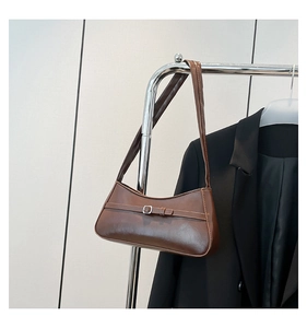 Detail of dark brown leather baguette bag featuring a silver buckle and sleek texture