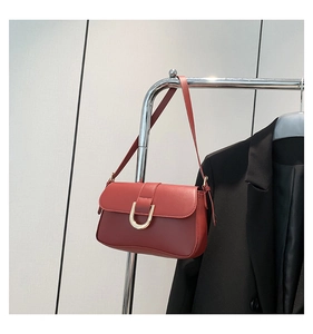 Detail of burgundy leather shoulder bag with gold horseshoe buckle on a metal hanger