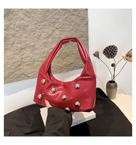 Détail du sac croissant en cuir verni rouge avec clous métalliques argentés et poignée torsadée