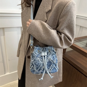 Light blue quilted denim drawstring bucket bag with adjustable leather shoulder strap