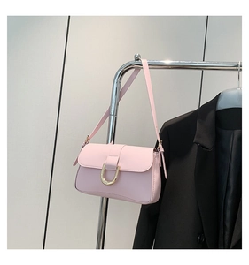 Detail view of pink minimalist handbag with polished gold U-shaped metal buckle closure